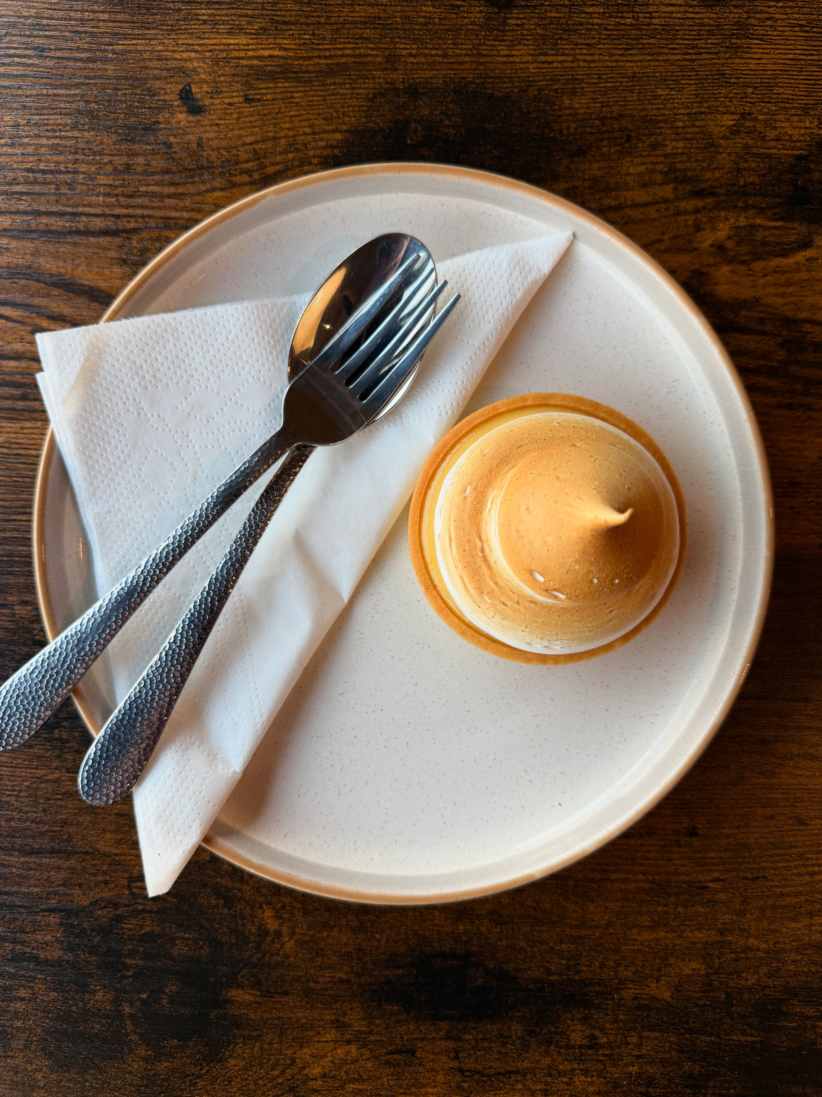 Lemon meringue tart with a torched meringue top, served on a white plate with cutlery at Krumb Bakery, Belfast